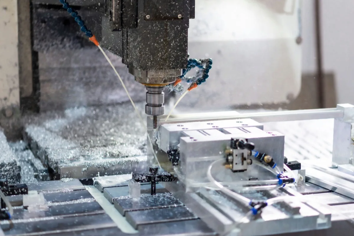 CNC-Bearbeitungszentrum fräst ein Aluminiumteil unter Kühlschmierstoff